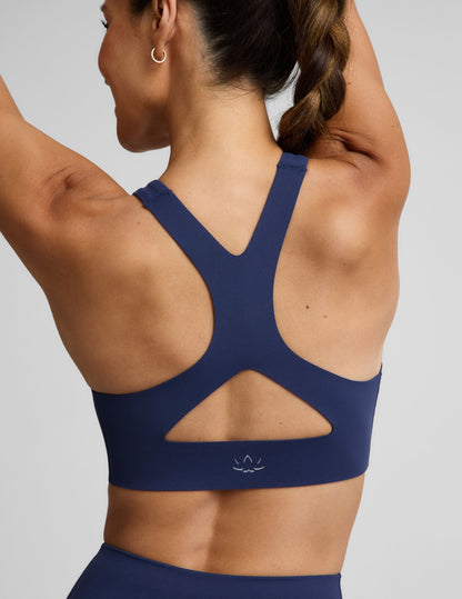 Woman wearing a blue sports bra and blue biker shorts against a plain background.