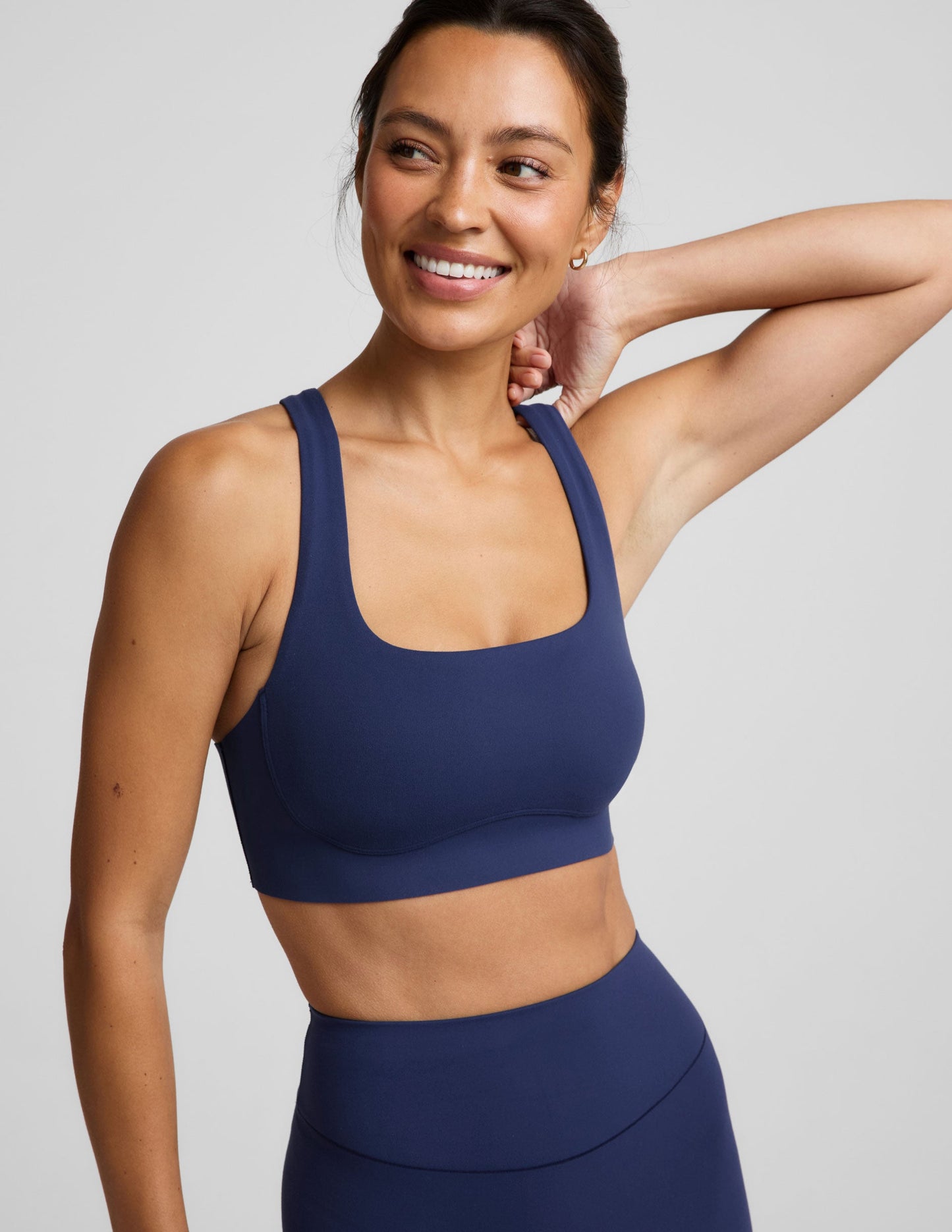 Woman wearing a blue sports bra and blue biker shorts against a plain background.