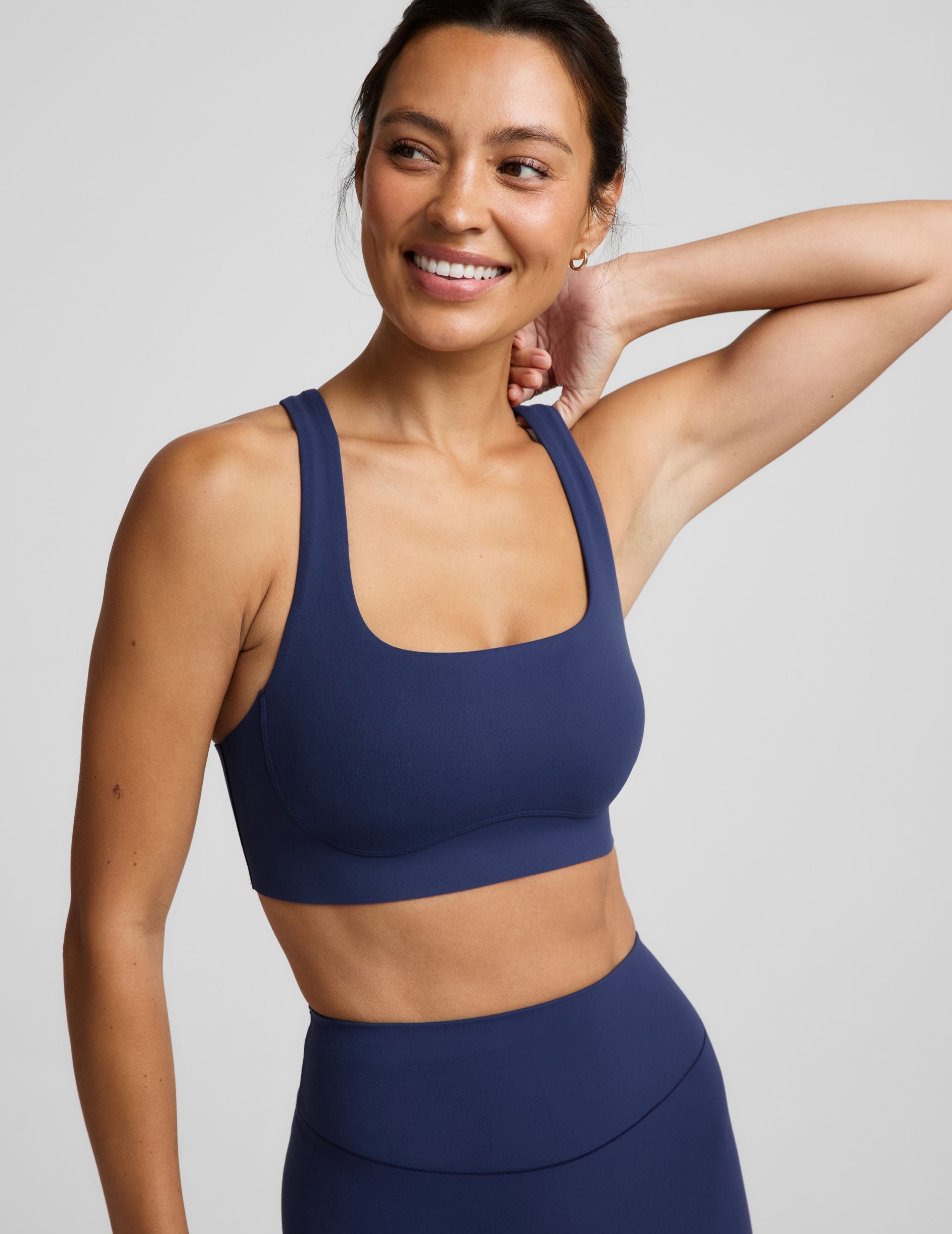 Woman wearing a blue sports bra and blue biker shorts against a plain background.