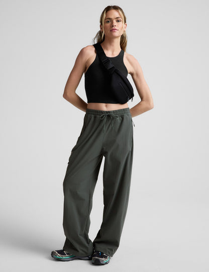 Woman wearing Java Peak Pant™ styled with a black crop tank and crossbody bag, featuring a bungee hem and cargo pockets.