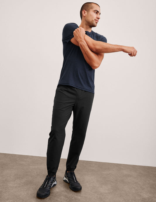 Man stretching in the dark On The Go Men's Jogger featuring a relaxed fit, elastic waistband, and cuffed ankles.