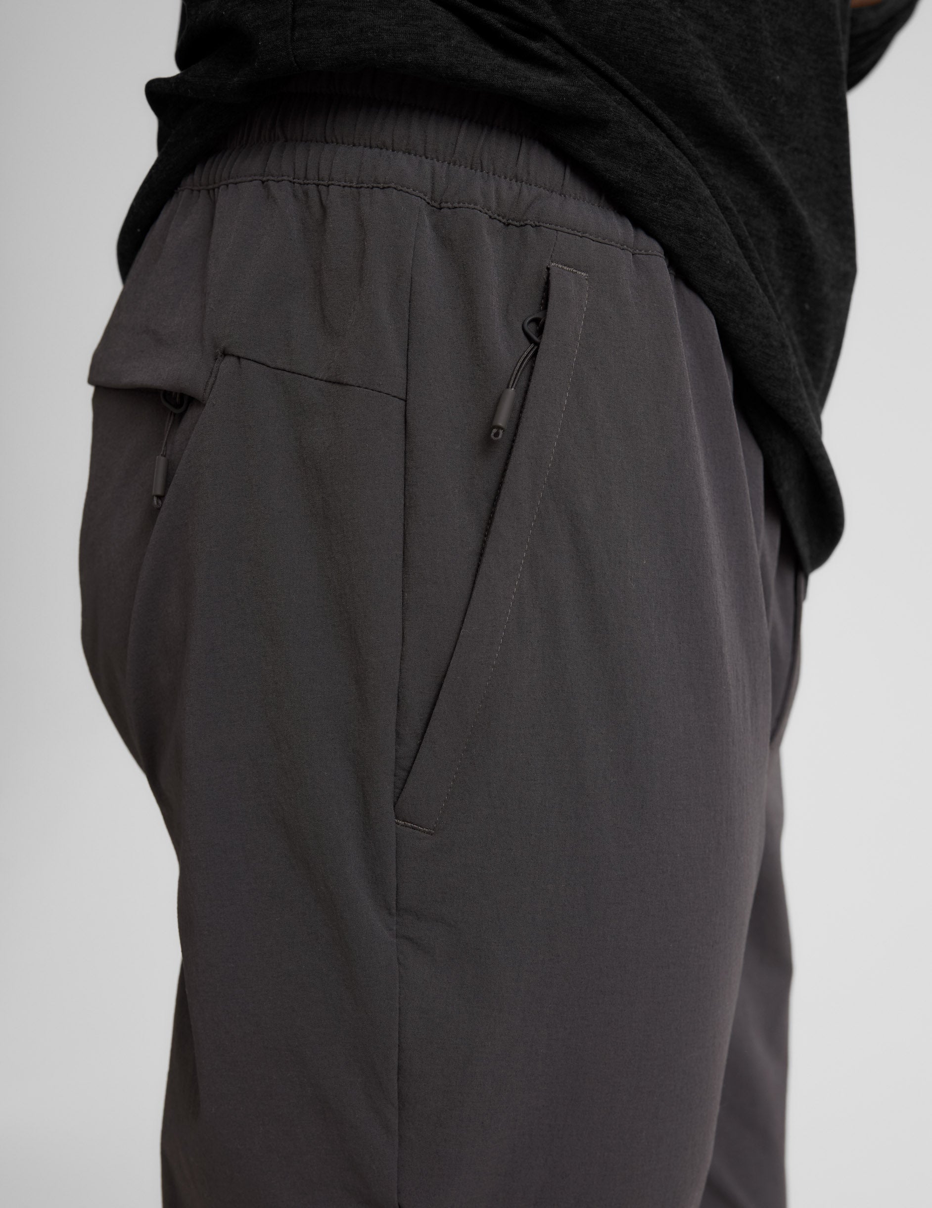 Side view of black Men's All Terrain Pant showing the elastic waistband and functional side and back zipper pockets.
