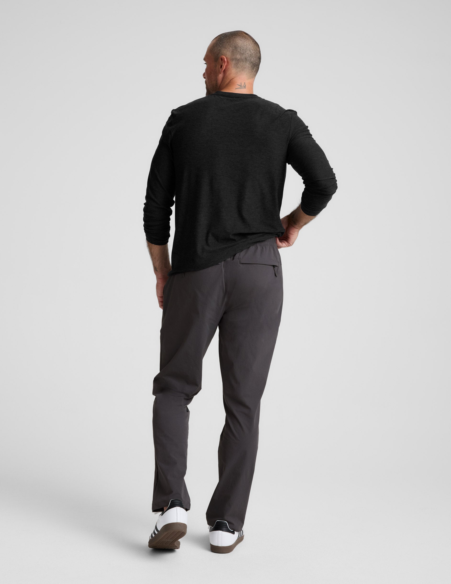 Back view of charcoal Men's All Terrain Pant on a model, showing the relaxed straight fit and zippered back pocket detail.