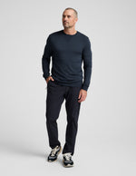 Man wearing navy Men's All Terrain Pant in a relaxed straight fit with zipper pockets, sweatshirt, and sneakers.