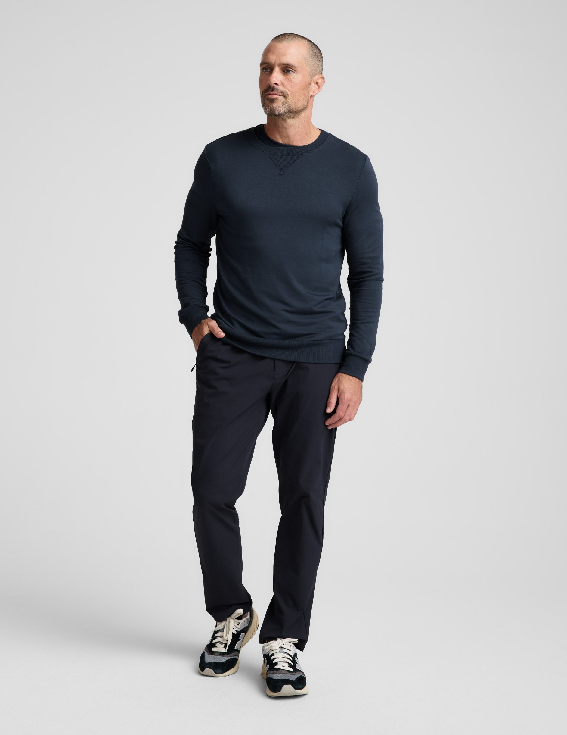 Man wearing navy Men's All Terrain Pant in a relaxed straight fit with zipper pockets, sweatshirt, and sneakers.