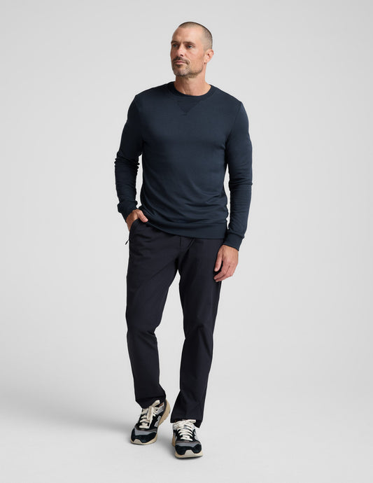 Man wearing navy Men's All Terrain Pant in a relaxed straight fit with zipper pockets, sweatshirt, and sneakers.