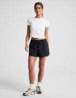 Woman wearing black Peak 3" Short™ with a white t-shirt, featuring an elastic drawstring waist and side cargo pockets.