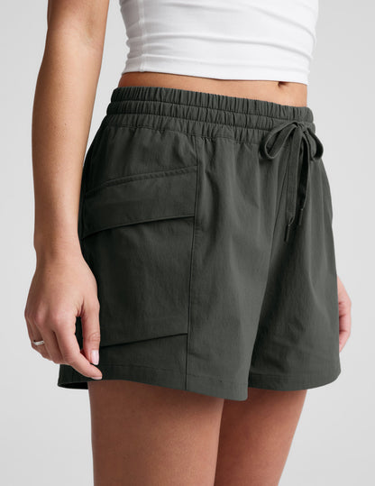 Side profile of woman wearing Black Peak 3" Short™ with a white cropped tank top, showing the side patch cargo pocket.