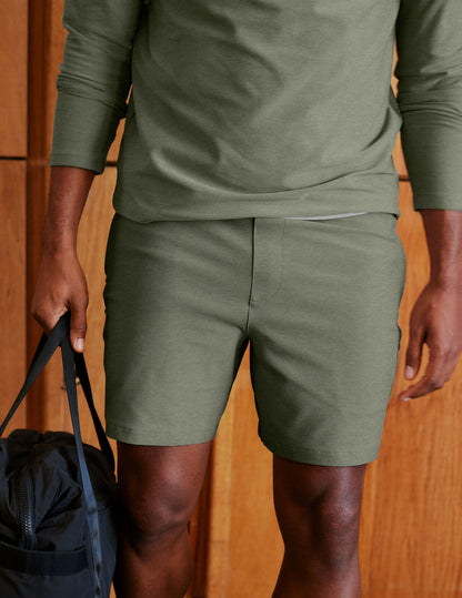 Man wearing Olive Spacedye™ Unlimited Men's Short paired with a matching long-sleeve top and holding a black bag.